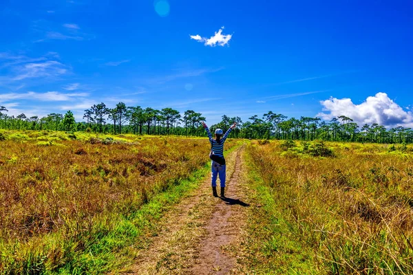 Mladá žena stojí na polní cestě na venkově za slunečného dne — Stock fotografie