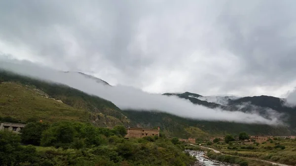 風光明媚な景観で霧に包まれている常緑針葉樹と雲の横の山の斜面 — ストック写真