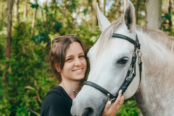 Smiling young woman affectionately hugging her chestnut horse after going for a ride — Stock Photo, Image