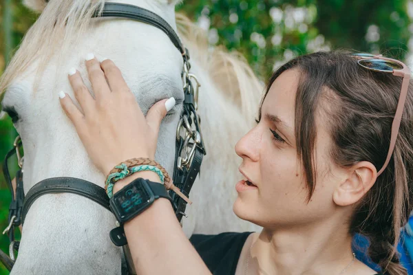 Girl scolding her white horse with her hands — Stock Photo, Image