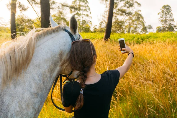 Female vet taking selfie with horse in sunset — Stock Photo, Image