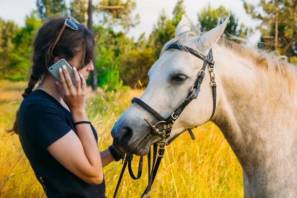 Tierärztin am Telefon, während sie auf dem Land am Pferd steht — Stockfoto