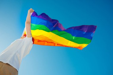 Kafasında LGBT bayrağı sallayan genç bir kadının düşük açılı görüntüsü