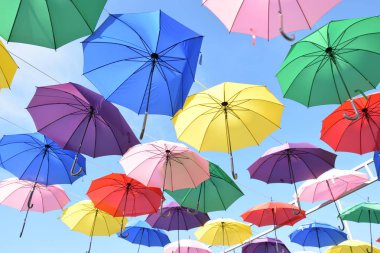 Gökyüzü arka planında renkli şemsiyeler, renkli şemsiyeler