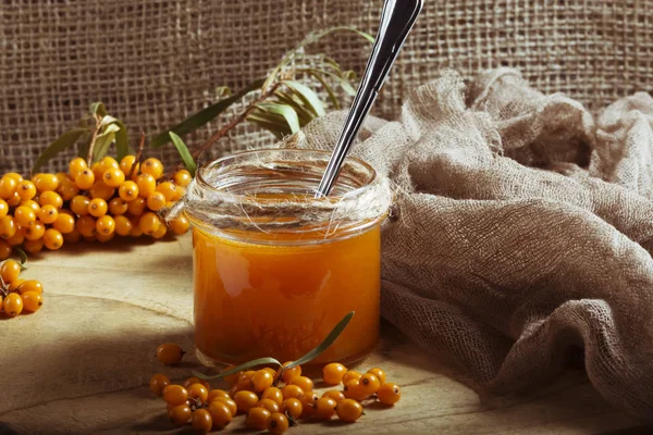 Homemade jam. Glass jar with sea buckthorn jam on  canvas  background. Source of vitamins in autumn and winter. Used in folk medicine for flu and colds.