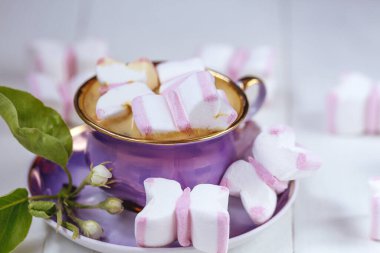 Ahşap arka planda elma çiçeği olan pembe ve beyaz şekerli bir fincan kahve. Yumuşak odak.