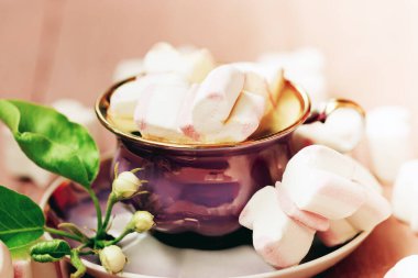 Ahşap arka planda elma çiçeği olan pembe ve beyaz şekerli bir fincan kahve. Yumuşak odak.