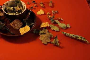 Harika, güzel sonbahar arkaplanı. Kahverengi bir kupada ve tabakta kuru sonbahar meşe yaprakları..