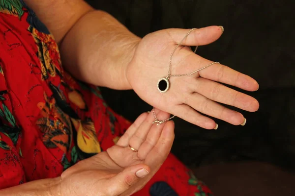 Overweight woman holding jewelry in her hands. On her hands are scars from burns. Plus size model