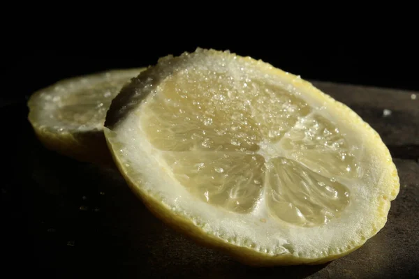 Fette rotonde di limone cosparse di zucchero o sale su fondo scuro — Foto Stock