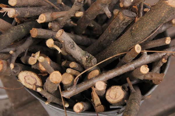 Madera de cepillo en un cubo para una estufa o chimenea cerca de una pared de ladrillo. Cesta de leña vieja en un suelo de madera rústico — Foto de Stock