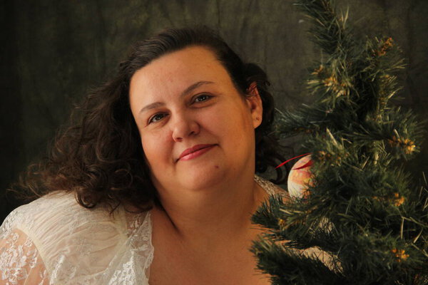 Толстая женщина украшает ёлку. Радость предстоящего праздника. Декор дерева
