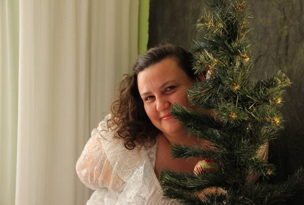 Толстая женщина украшает ёлку. Радость предстоящего праздника. Декор дерева
