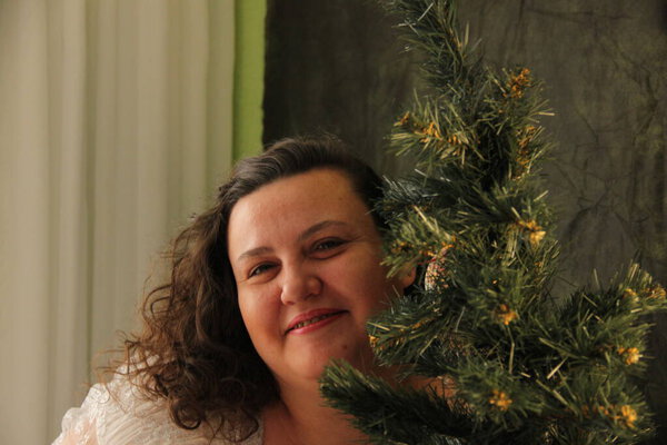 Толстая женщина украшает ёлку. Радость предстоящего праздника. Декор дерева
