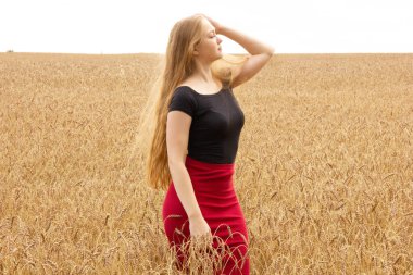 Mutlu genç kız altın olgun buğday tarlasında yürüyor