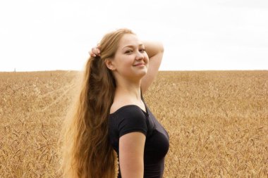 Mutlu genç kız altın olgun buğday tarlasında yürüyor