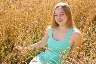 Mutlu genç kız altın olgun buğday tarlasında yürüyor