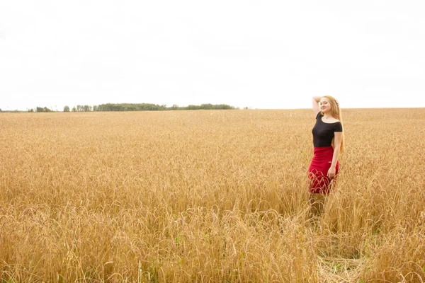 Happy young girl walks in a field of golden ripe wheat — Stock Photo, Image