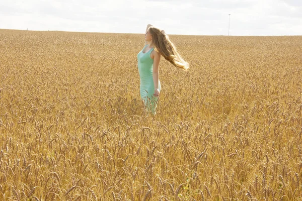 Happy young girl walks in a field of golden ripe wheat — Stock Photo, Image