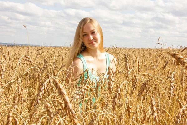 Glückliches junges Mädchen geht in einem Feld aus goldenem reifem Weizen — Stockfoto