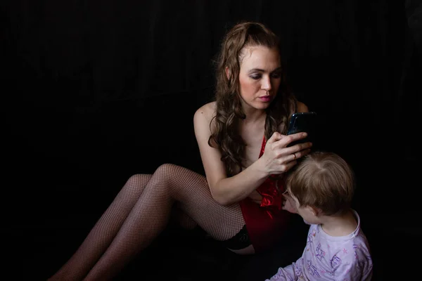 Mãe senta-se olha para o telefone não presta atenção à criança que se senta nas proximidades — Fotografia de Stock