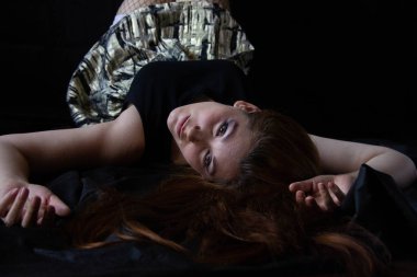 Seksi sakin kadın sırt üstü yatıyor. Siyah bir arkaplanda şefkat ve rahatlama.