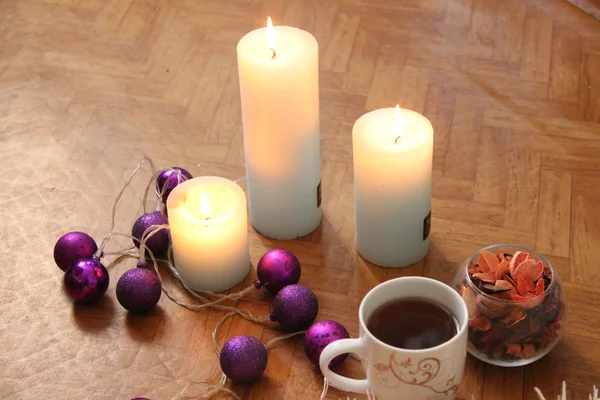 Brandende kaarsen naast paarse slinger ballen. — Stockfoto