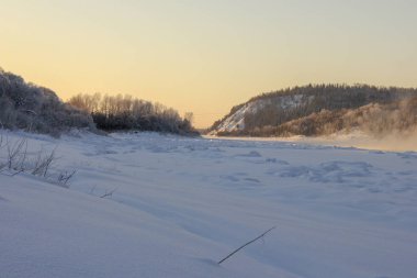 Karla kaplı tepeler, yamaçlarda yemyeşil ağaçlar, günbatımında. Bir sürü kar ve don ağacı var.. 