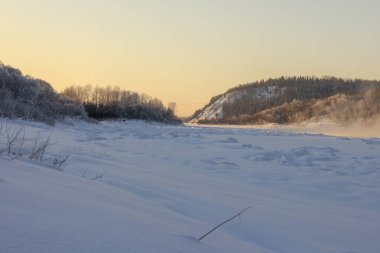 Karla kaplı tepeler, yamaçlarda yemyeşil ağaçlar, günbatımında. Bir sürü kar ve don ağacı var.. 
