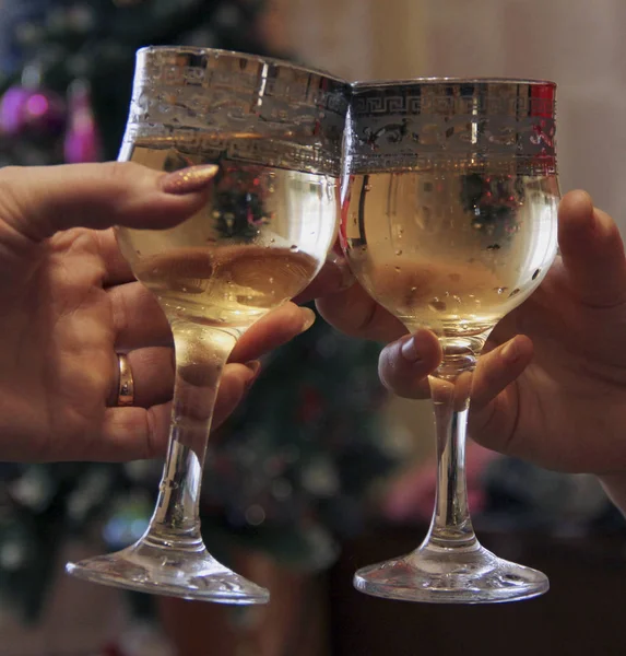 Mãos segurar copos de champanhe contra o fundo da árvore de Natal. Celebrar um evento importante — Fotografia de Stock