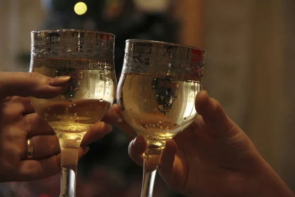 Mãos segurar copos de champanhe contra o fundo da árvore de Natal. Celebrar um evento importante — Fotografia de Stock