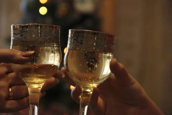 Mãos segurar copos de champanhe contra o fundo da árvore de Natal. Celebrar um evento importante — Fotografia de Stock