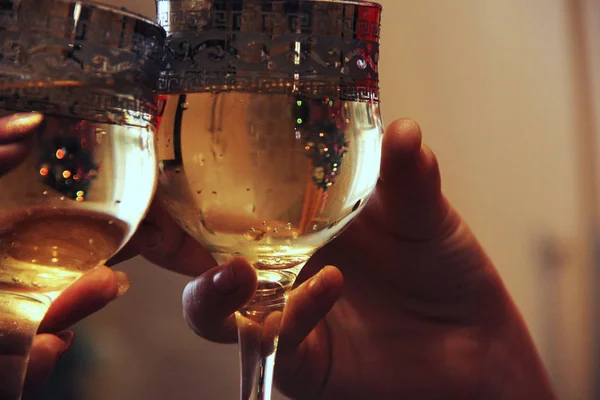 Mãos segurar copos de champanhe contra o fundo da árvore de Natal. Celebrar um evento importante — Fotografia de Stock