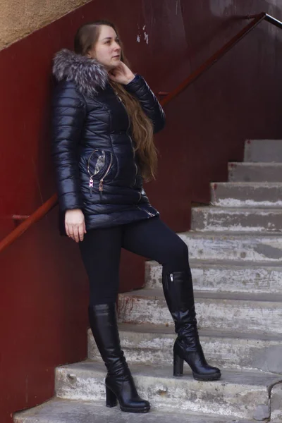긴 머리를 계단에 늘어뜨린 채 재킷을 입은 한 소녀가 포즈를 취한다. — 스톡 사진