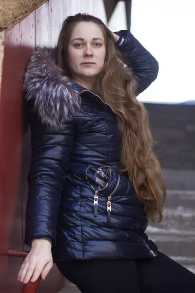 긴 머리를 계단에 늘어뜨린 채 재킷을 입은 한 소녀가 포즈를 취한다. — 스톡 사진