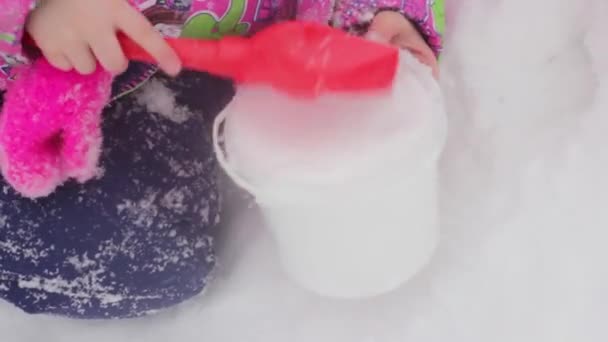 赤ちゃんの手はスクープを保持し バケツの中の雪を拾う 冬の子供の楽しみ — ストック動画