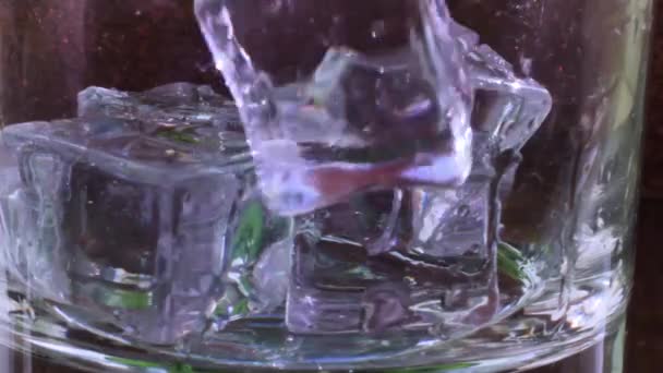 透明なガラスに氷のキューブが落下し 透明な液体 水または透明なアルコールが注がれます — ストック動画
