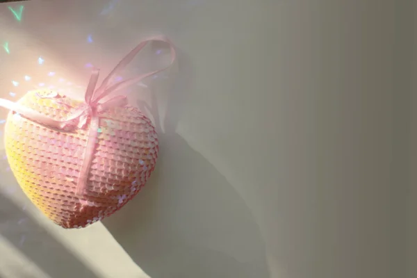 Beyaz arka planda pembe pullu bir kalp. Mesaj için yer. Güneşten gelen kağıtta parla.