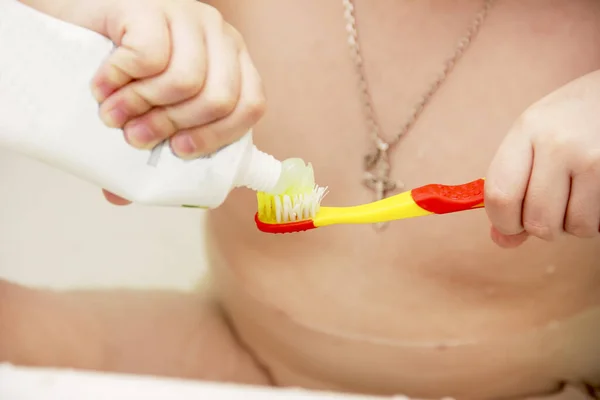The little girl sits in the bath and brushes her teeth. Child hygiene of the mouth and body