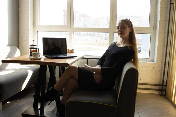 검은 옷을 입은 한 아름다운 소녀 가창 옆 탁자에 앉아 있다. 작업이나 컴퓨터 교육을 중단하라 — 스톡 사진