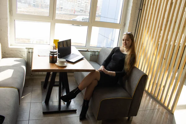 검은 옷을 입은 한 아름다운 소녀 가창 옆 탁자에 앉아 있다. 작업이나 컴퓨터 교육을 중단하라 — 스톡 사진