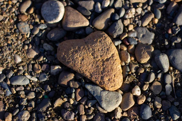 La piedra, que se asemeja a la forma de un corazón, se encuentra en pequeñas piedras — Foto de Stock