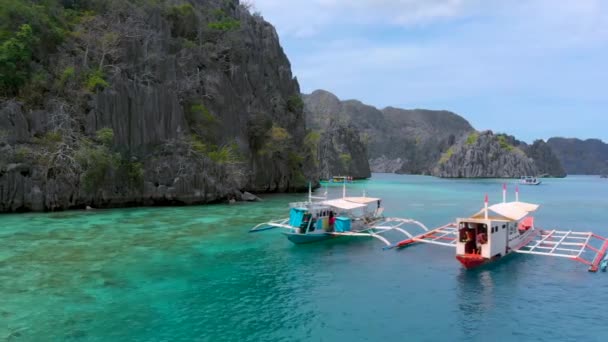 필리핀, 코론 섬의 청록색 물 위에 있는 절벽 근처에 있는 관광객 배들 — 비디오