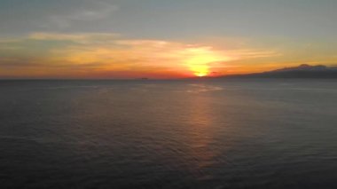 Filipinler 'de gün batımında okyanusun üzerinde sineklerin sineklerle yaptığı hareketler. Tropikal okyanus günbatımının hava manzarası. Siquijor Adası 'ndaki deniz yüzeyinde turuncu güneş yansıması..