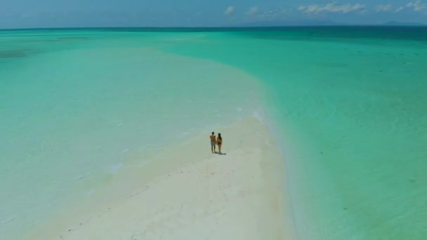 4K在菲律宾巴拉望的曼萨兰根沙洲 一对可爱的旅行情侣站在无尽的白沙滩上 四周环绕着碧绿的水 — 图库视频影像