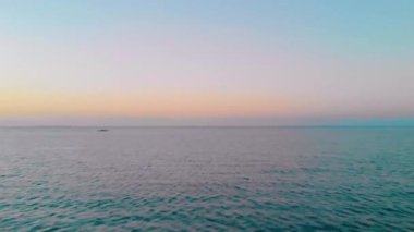 Deniz seviyesinden 4K hava hareketi. Filipinler 'de Balabac, Balabac, Palawan Candaraman Adası' ndaki bir okyanus yüzeyine renkli günbatımı ve yansıyan güneş