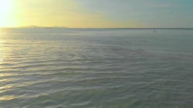 4k Havadan deniz üzerinde turuncu gün batımı görüntüsü ve Onok Adası, Balabac, Filipinler 'deki Palawan' da okyanus yüzeyine yansıyan güneşi yansıtıyor.