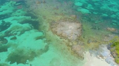 Filipinler 'deki sonsuz gök mavisi rengiyle çevrili, turkuaz su ve mercan adasının ortasında kaya oluşumlarının 4k havası.