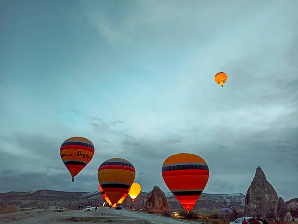 在土耳其 多彩的热气球在冬季清晨飞越卡帕多西亚上空 而在黑暗的早晨飞行 — 图库照片