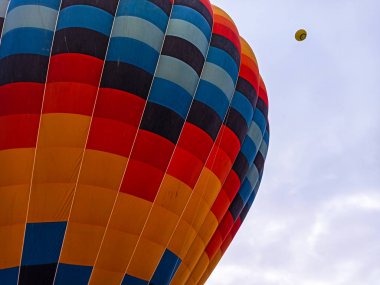 Türkiye 'nin Kapadokya kentindeki kayalık araziyle güneşin doğuşunda uçan renkli sıcak hava balonları